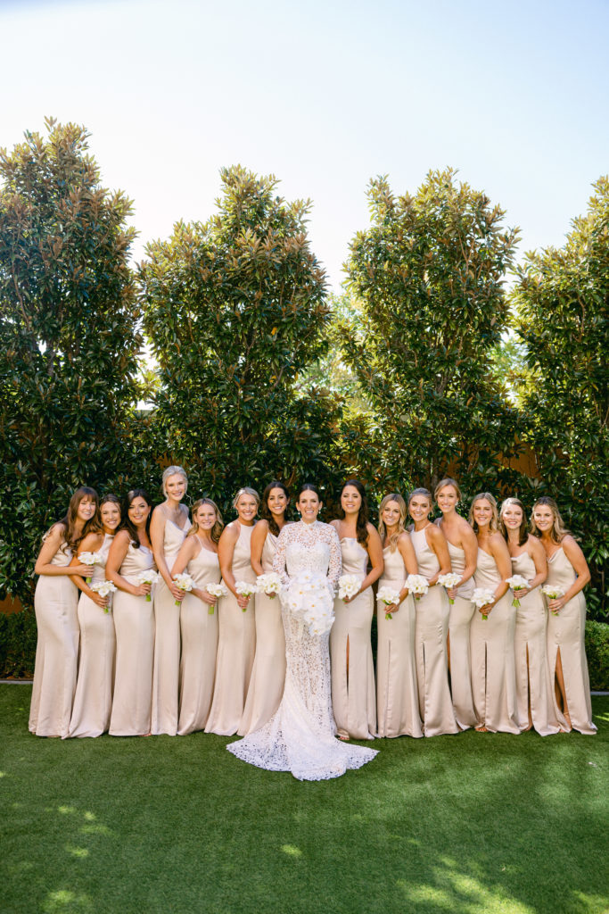 Bride and her wedding attendants in matching beige dresses.