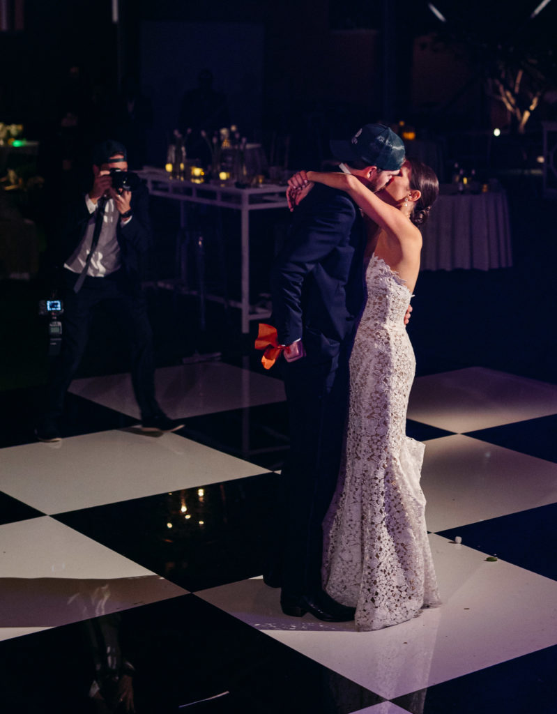 Wedding Reception last dance on a checkered dance floor. Couple wearing custom branded hats for the event with thier wedding logo. Photographer Carter Rose seen in background capturing the moment.