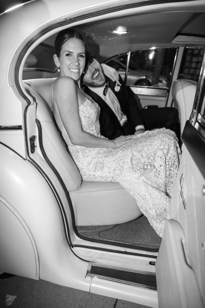 Bride and groom sitting in the the vintage getaway car outside of their wedding reception at the Rosewood Mansion on Turtle Creek